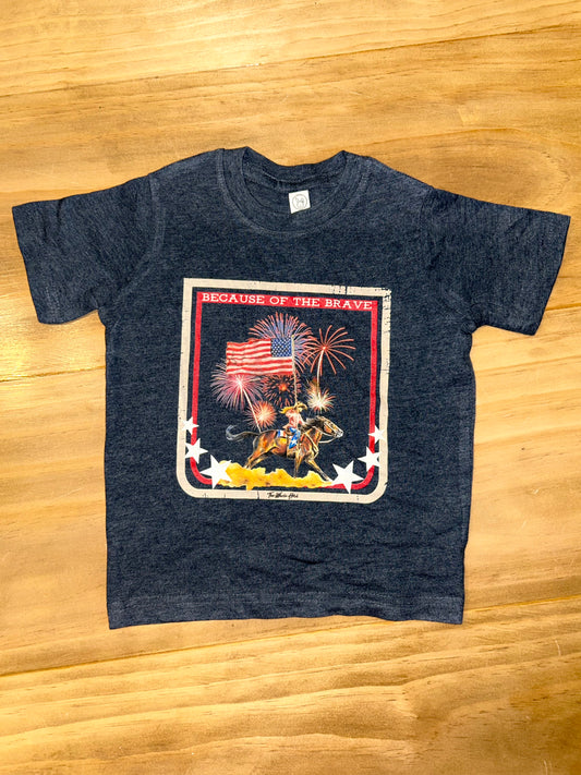 Western Toddler or Youth T-Shirt in the cover navy blue, displaying a cowgirl on her horse holding the American Flag, and the words 'Because of the Brave'