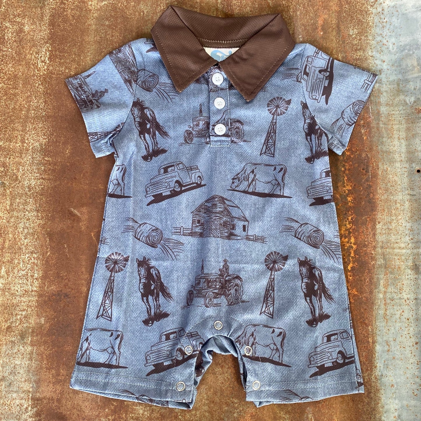 "Blue baby romper with western-themed print featuring horses, cows, and a barn"